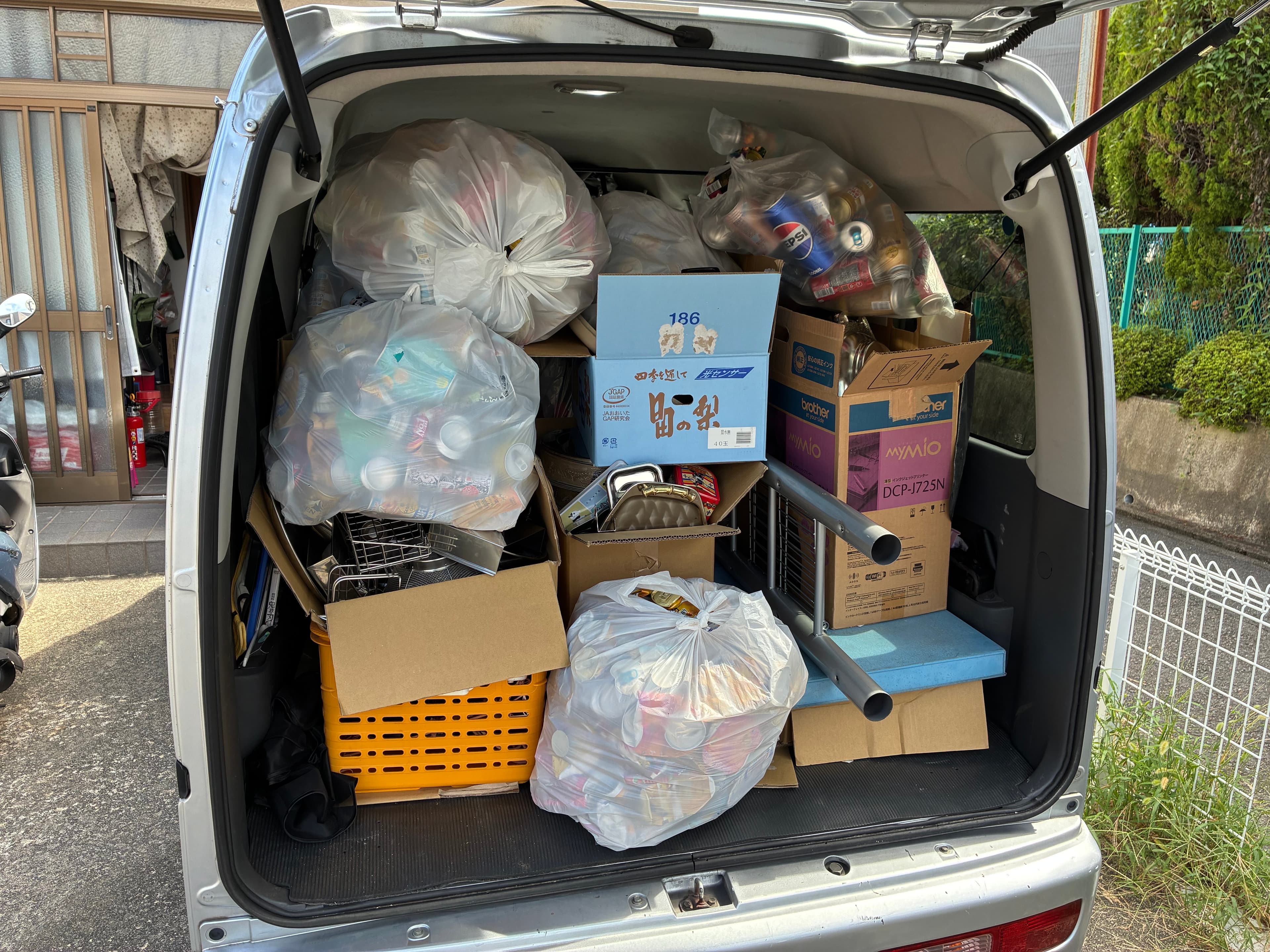 回収した不用品の袋や段ボール、かごを積み込んだ軽貨物バンの荷台